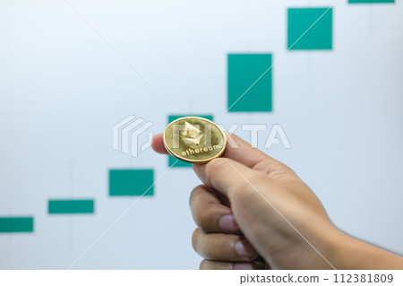 Ethereum physical coin symbol on a laptop with uptrend price graph background, future concept financial currency, cryptocurrency sign. 112381809