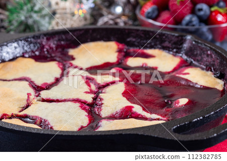 Homemade berry cobbler in cast iron skillet, Christmas decoration on background, horizontal, closeup 112382785