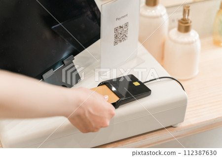 A woman making credit card payment, online payment, and cashless payment at a beauty salon/hair salon (electronic payment) 112387630