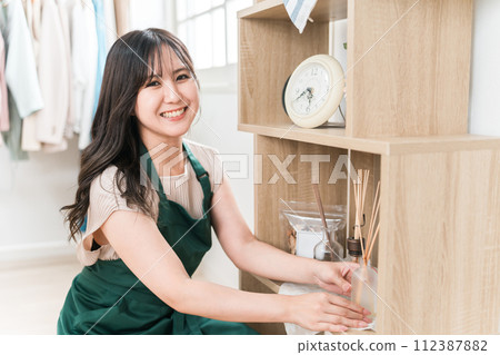 Female staff holding aroma oil at general store/apparel/interior/craft shop 112387882