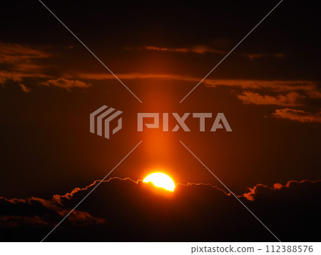 A sun pillar extending from the sun sinking into a sea of clouds 112388576