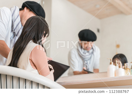 Male hairdresser handing a tablet to a female customer at a beauty salon (e-book, questionnaire, menu, accounting) 112388767