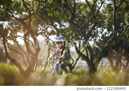 little asian girl riding bike outdoors in city park little asian girl riding bike outdoors in city park 112389493