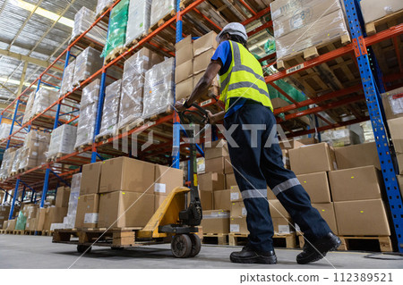 Man African American worker wear safety uniform push load cart product to shelf in warehouse store. 112389521