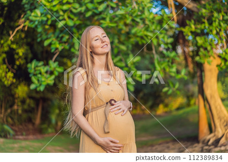 pregnant woman finds joy and serenity, relishing a tranquil moment outdoors during her pregnancy journey 112389834
