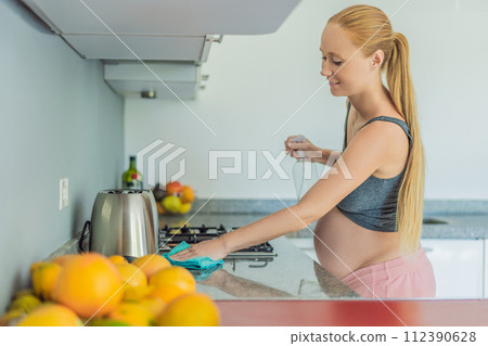 Efficient and dedicated, a pregnant woman tackles kitchen chores, ensuring a clean and organized space, exemplifying resilience and care during her pregnancy 112390628