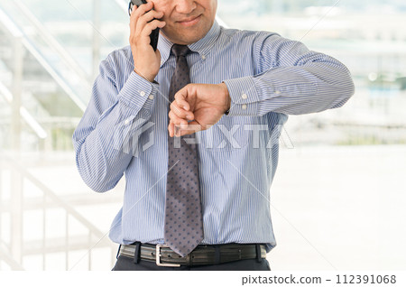 中年男性亞裔商人在辦公大樓用智慧型手機交談(遲到、麻煩、麻煩、會議) 中年男性亞裔商人在辦公大樓用智慧型手機交談(遲到、麻煩、麻煩、會議) 112391068