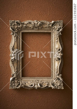 Antique picture frame hung on brown wallpaper 112391687