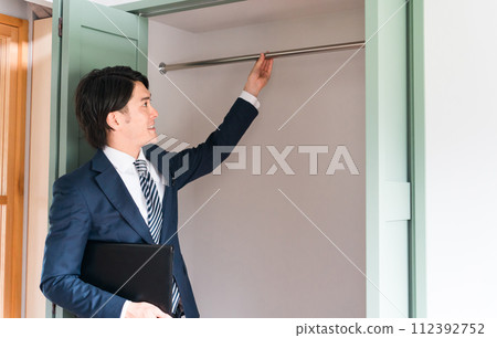 A male businessman who is a planner/salesman/adviser for a house builder showing a closet 112392752