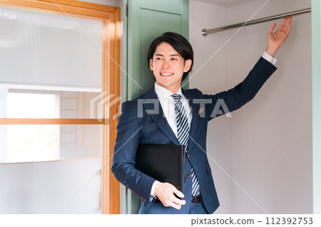 A male businessman who is a planner/salesman/adviser for a house builder showing a closet A male businessman who is a planner/salesman/adviser for a house builder showing a closet 112392753