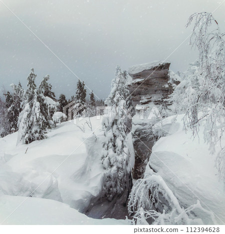Big granite rock is frozen and covered with snow. 112394628