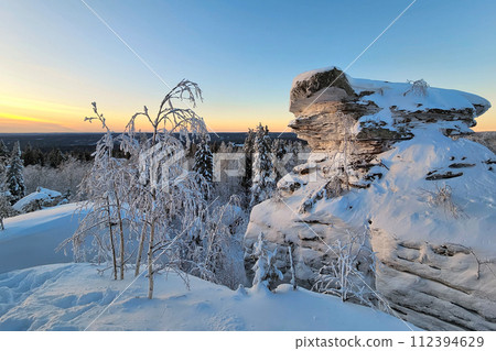Amazing snow-covered stone cliff at sunset. Amazing snow-covered stone cliff at sunset. 112394629