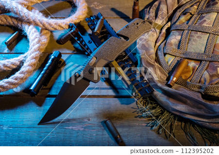 A folding knife with a green handle and a black blade. Military composition with a knife and bullets. A folding knife with a green handle and a black blade. Military composition with a knife and bullets. 112395202