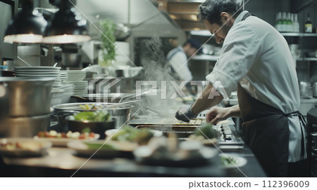 An expert chef focused on perfecting a dish in the bustling environment of a professional kitchen, where culinary art meets precision 112396009