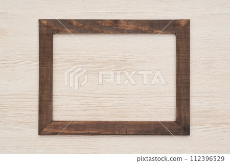 Wooden frame hung on a beige plank wall 112396529