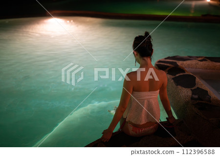 A woman relaxing in the pool at night 112396588
