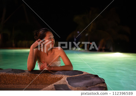 A woman relaxing in the pool at night A woman relaxing in the pool at night 112396589