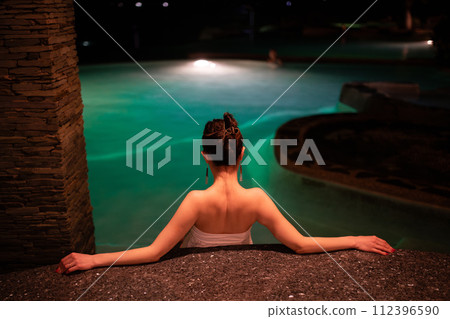A woman relaxing in the pool at night A woman relaxing in the pool at night 112396590