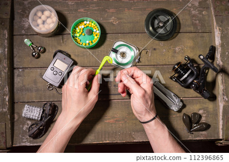 Knitting fishing loops. Fisherman getting ready to go fishing. Fishing composition. 112396865
