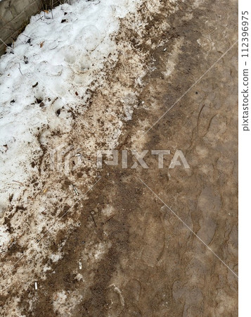 Melting dirty snow on the streets of the city during the daytime in winter. Snow with sand and mud lies on the road Melting dirty snow on the streets of the city during the daytime in winter. Snow with sand and mud lies on the road 112396975