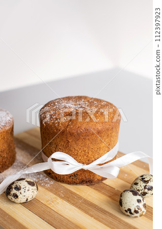 Easter pastries, sponge cake with a white bow is on the board. Quail eggs. Place for text Easter pastries, sponge cake with a white bow is on the board. Quail eggs. Place for text 112397923