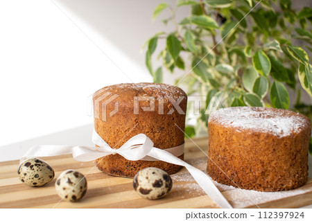Sponge cake with powdered sugar on the table with quail eggs. A green plant. Place for text Sponge cake with powdered sugar on the table with quail eggs. A green plant. Place for text 112397924