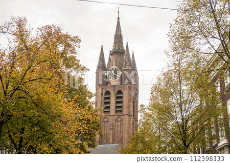 The Netherlands, Delft, October, 2022 The old church in Delft against the background of autumn trees The Netherlands, Delft, October, 2022 The old church in Delft against the background of autumn trees 112398333