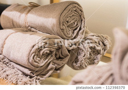 Rolled Beige Textured Throws on Wooden Shelf Rolled Beige Textured Throws on Wooden Shelf 112398370