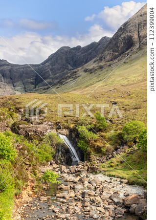 Slender waterfall feeding Fairy Pools with Isle of Skye's Cuillin mountains in the backdrop Slender waterfall feeding Fairy Pools with Isle of Skye's Cuillin mountains in the backdrop 112399004