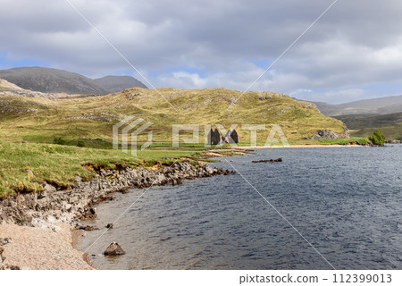 Ruins of Calda House against the Scottish Highlands, rugged hills and serene lake reflections 112399013