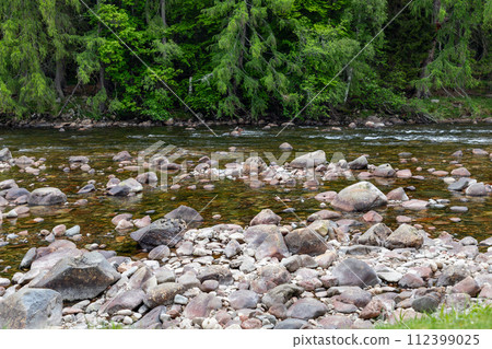 Serene river flow in Scotland, surrounded by greenery, with stones creating natural art Serene river flow in Scotland, surrounded by greenery, with stones creating natural art 112399025