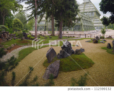Japanese garden in Vienna (inside Botanical garden): Japanese maple, topiary small pine trees, stepping stones, moss, small stream among trees 112399132