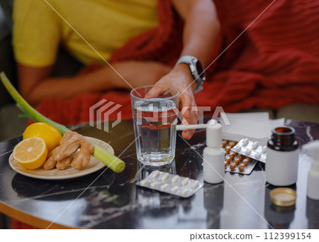 Ginger, lemon, onion and different drugs on table on background sick man. Alternative remedies and traditional pills to treat colds and flu. Natural medicine vs conventional medicine concept Ginger, lemon, onion and different drugs on table on background sick man. Alternative remedies and traditional pills to treat colds and flu. Natural medicine vs conventional medicine concept 112399154
