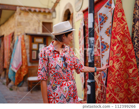 female summer travel to Antalya, Turkey. young asian woman in red dress walk old town Kalechi , female tourist traveler discover interesting places and popular tourist attraction, look on capret 112399266