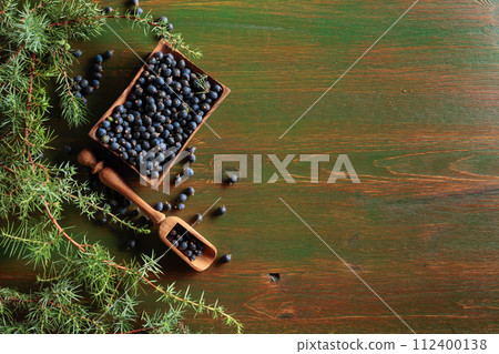 Juniper branches and seeds on a wooden background. 112400138