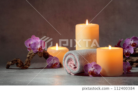 Towels, orchid flowers, and burning candles. 112400384