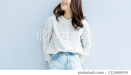Smiling woman standing in front of a wall 112400654