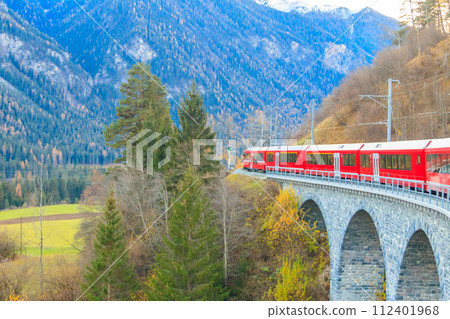 Red passenger train on Rhaetian railway in Canton Graubunden, Switzerland at autumn Red passenger train on Rhaetian railway in Canton Graubunden, Switzerland at autumn 112401968