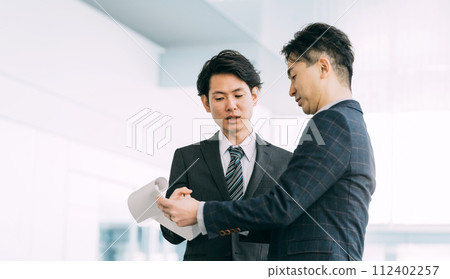 兩名男商人一邊看文件一邊開會 兩名男商人一邊看文件一邊開會 112402257