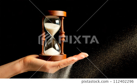 Hand of a Woman Holding an Hourglass on a Black Background - Generative Ai 112402296