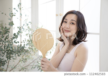 Beauty Woman holding a mirror by the window Beauty Woman holding a mirror by the window 112402583