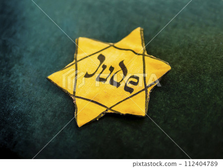 Yellow Star of David outlined in black with the German word for "Jew" written in Hebrew style on canvas, used by the Nazis during the Holocaust to identify Jews Yellow Star of David outlined in black with the German word for "Jew" written in Hebrew style on canvas, used by the Nazis during the Holocaust to identify Jews 112404789