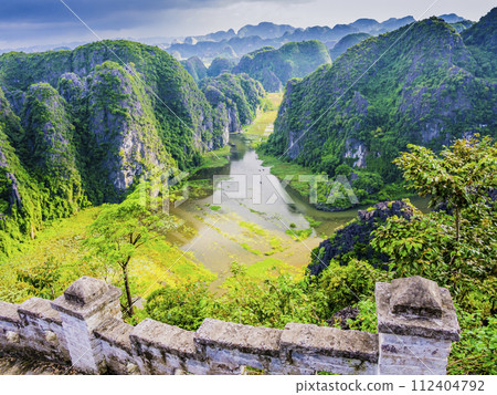 Impressive karst formations and rice paddy fields in Tam Coc with the stone staircase ascending the lying dragon in foreground, Ninh Binh province, Vietnam Impressive karst formations and rice paddy fields in Tam Coc with the stone staircase ascending the lying dragon in foreground, Ninh Binh province, Vietnam 112404792