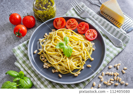 Traditional italian spaghetti pasta pesto with fresh basil leaves and ingredients on gray background Traditional italian spaghetti pasta pesto with fresh basil leaves and ingredients on gray background 112405080