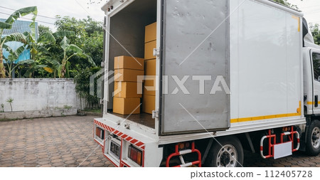 Outdoor scene, White delivery van and open car trunk carrying cardboard boxes. Logistic service for transporting items. House relocation. Moving Day Concept. 112405728