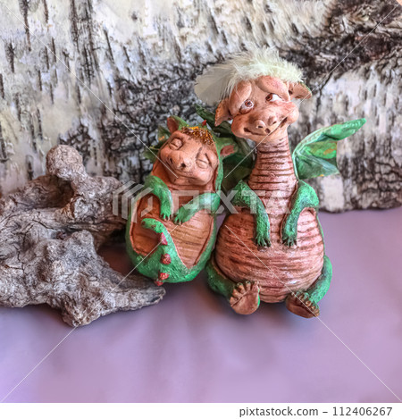 Two handmade dolls of green mama and baby dragons with wings on birch bark background 112406267
