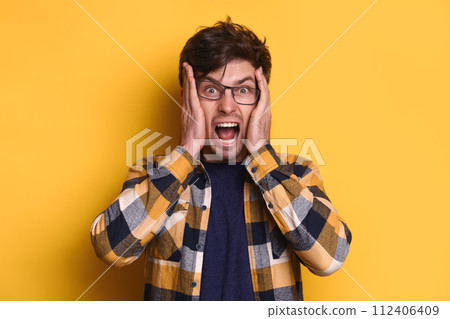 Stressed handsome man screaming against yellow studio background 112406409