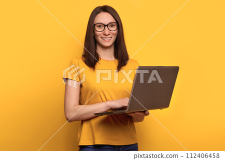 Smart beautiful young girl using laptop pc computer isolated on yellow background Smart beautiful young girl using laptop pc computer isolated on yellow background 112406458