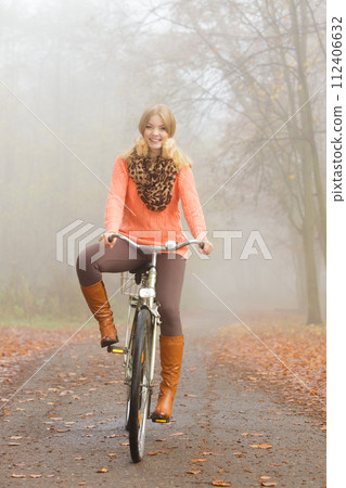 Happy active woman riding bike in autumn park. 112406632