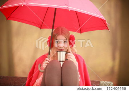 Girl sitting in park with umbrella 112406666